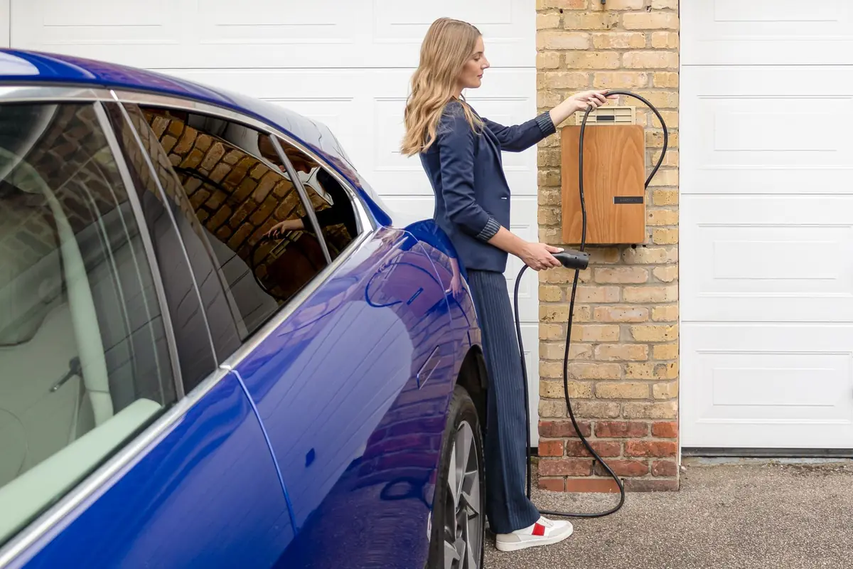 Conductrice branchant le câble de recharge de sa voiture électrique sur une wallbox