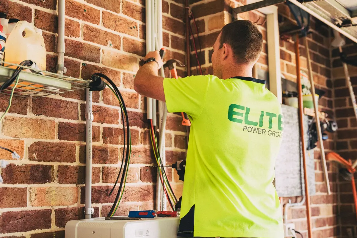 Électricien passant des câbles électriques le long du mur d’un garage