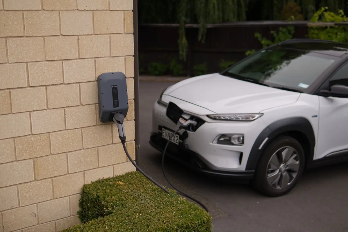 Wallbox fixée sur un mur extérieur, câble branché sur une voiture électrique